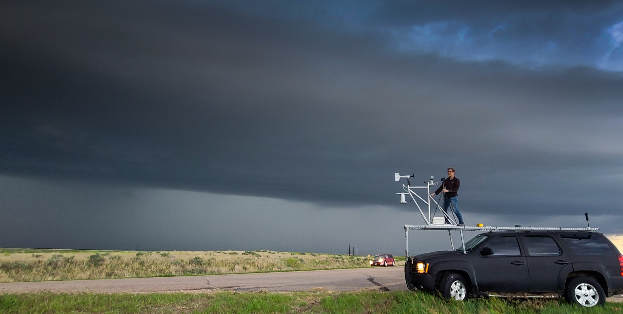 TJ Corrigan atop car with storm chasing equipment