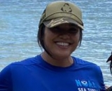 Sefa Muñoz in cap in front of ocean
